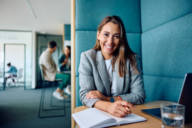Happy female entrepreneur working in office and looking at camera.