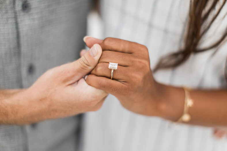 woman and man holding hands while displaying their proposal diamond ring