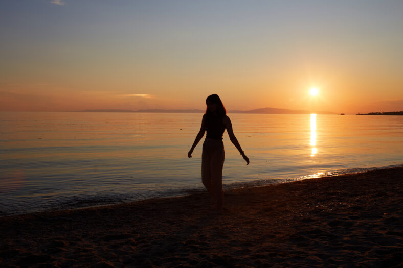 A pretty girl enjoys the sunset on a sandy beach. Summer travel, vacations at sea.