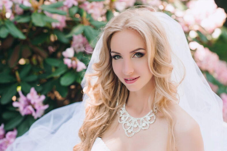 Portrait of a young beautiful bride on the nature, hairstyle, make-up