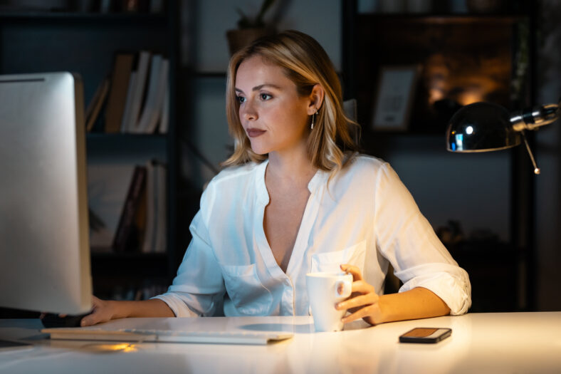 Shot of beautiful entrepreneur woman working with laptop while drinking a cup of coffee sitting in the office.