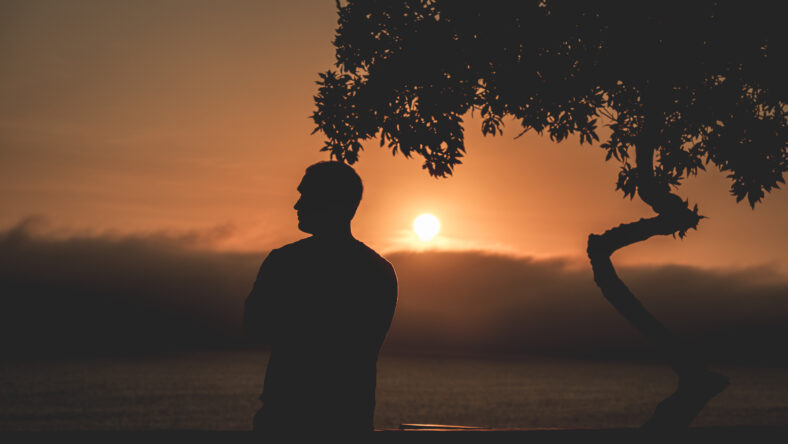 Dark silhouette of a man admiring the sunset from a Miraflores viewpoint over the Pacific Ocean in Lima, Peru.