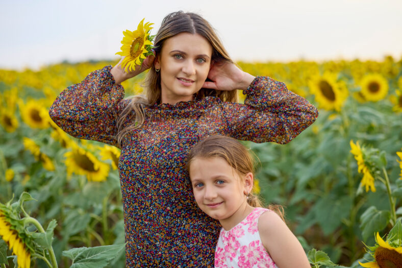 A mother with her little girl on a farm enjoying a sunflower field on a summer day
