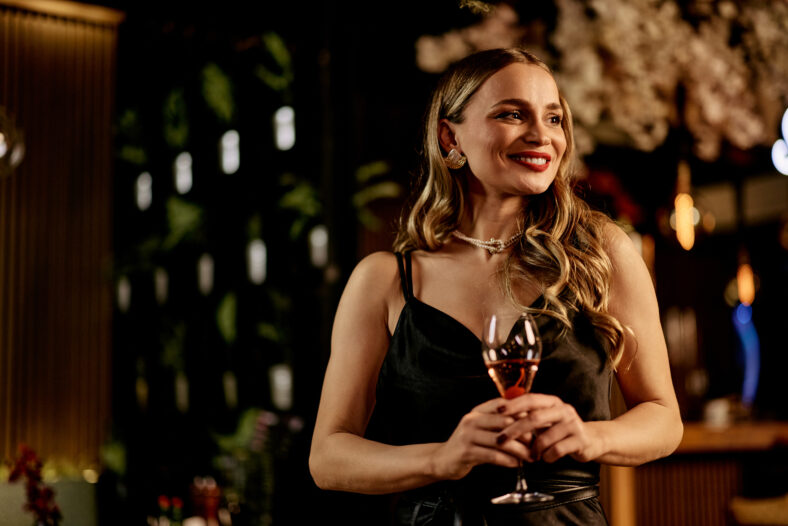 Elegant woman enjoying a glass of wine in a beautifully lit venue