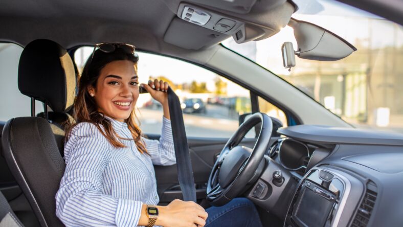 Safety first. Beautiful caucasian lady fastening car seat belt. Pretty young woman driving her new car. Pretty young woman driving her new car. Female fastening safety belt in car