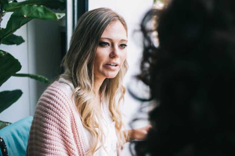 Beautiful caucasian blonde woman with trendy hairstyle sitting in cafe interior on break talking with somebody, attractive 20s hipster girl enjoying leisure on lunch break in restaurant on meeting