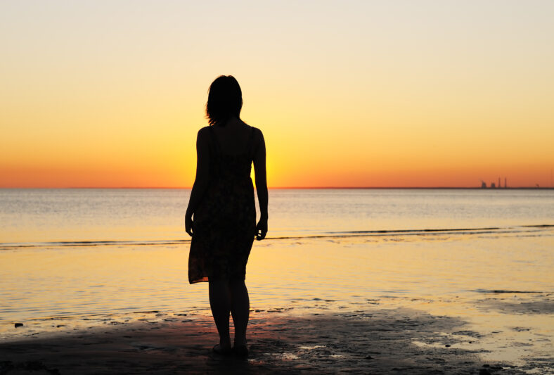 Portrait of young woman as silhouette by the sea