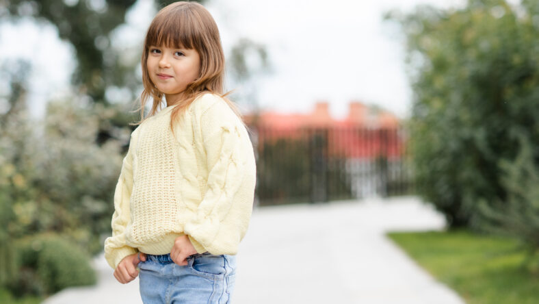 Cute little baby girl 4-5 year old wear casual clothes walk in park outdoor. Looking at camera. Springtime. Childhood.