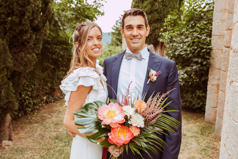 Beautiful wedding couple portrait. Bride and husband posing with a bouquet of flowers outdoors looking at camera.