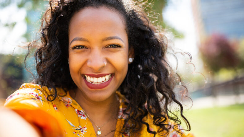 Close up portrait of pretty young african american woman taking selfie outside