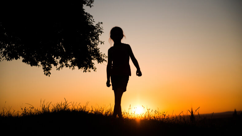 silhouette of a beautiful teen girl standing on a background of gorgeous sunsets