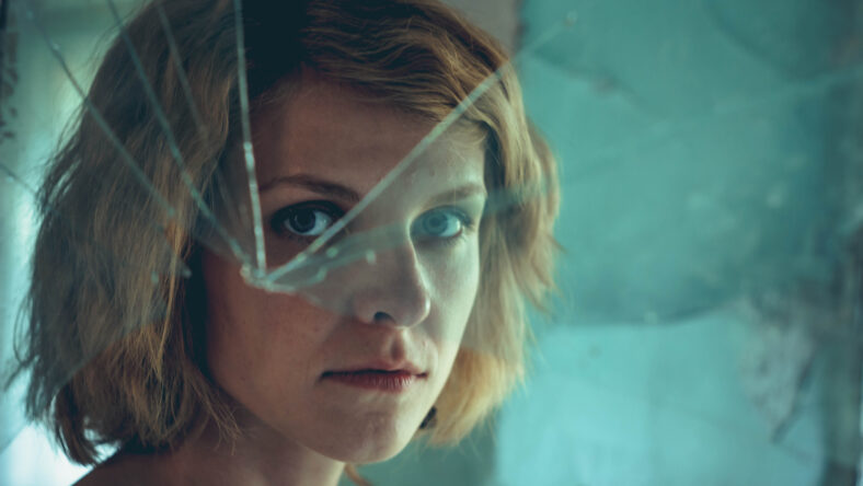 Woman looking through dirty broken glass closeup