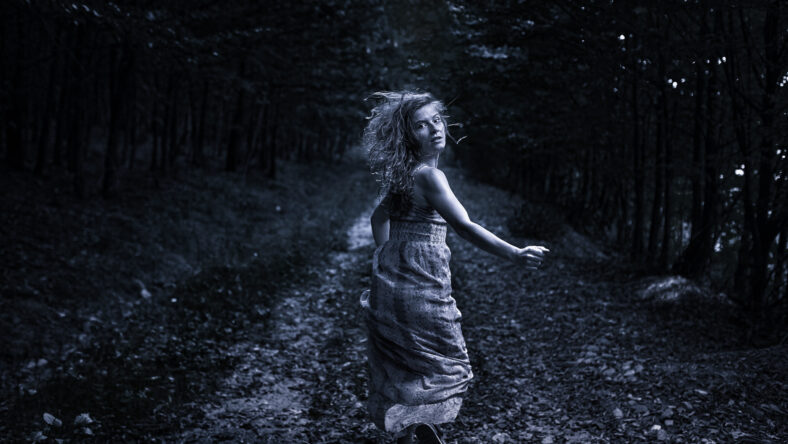Scared woman running through the forest