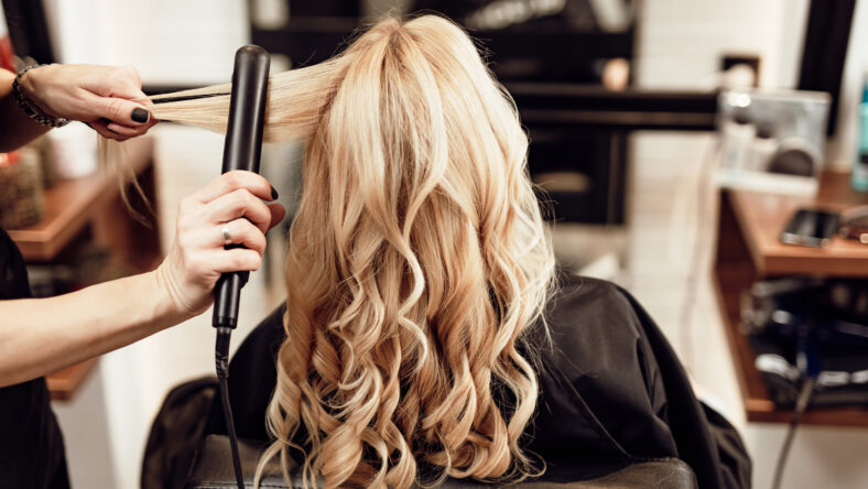Beautiful hairstyle of blond middle-aged woman in modern hair salon.