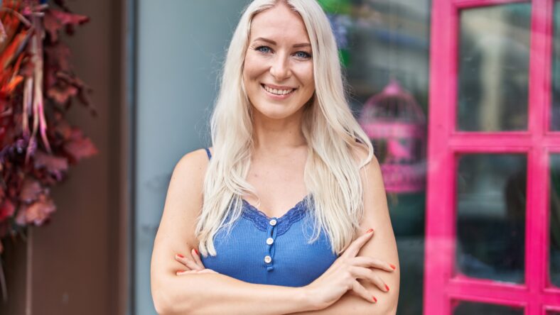 Young blonde woman smiling confident standing with arms crossed gesture at street