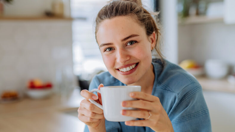 Young woman enjoying cup of coffee at morning, in a kitchen.