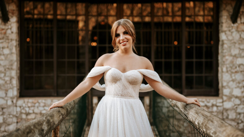 Beautiful bride portrait standing on wooden bridge with stone house behind