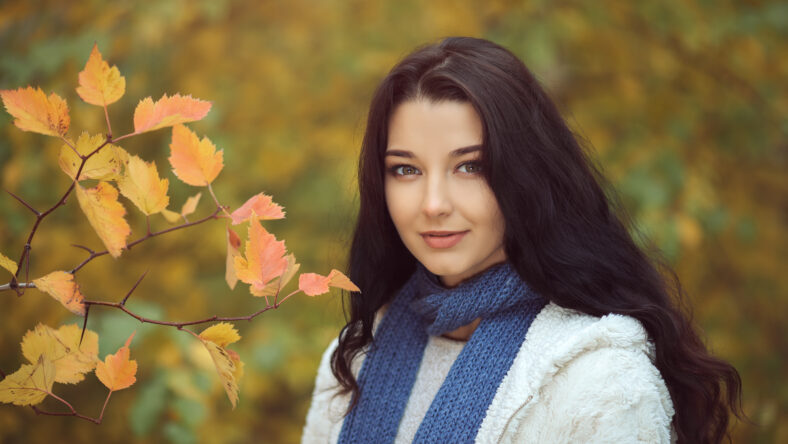 Autumn girl walking in city park. Fall woman portrait of happy lovely and beautiful mixed race Asian Caucasian young woman in forest in fall colors. Model in white casual clothes looking at camera