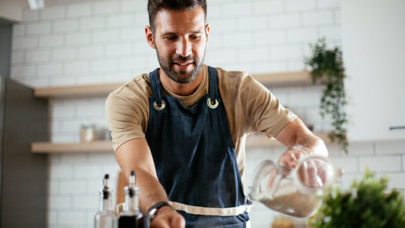 Handsome man preparing pasta in the kitchen. Guy cooking a tasty meal.