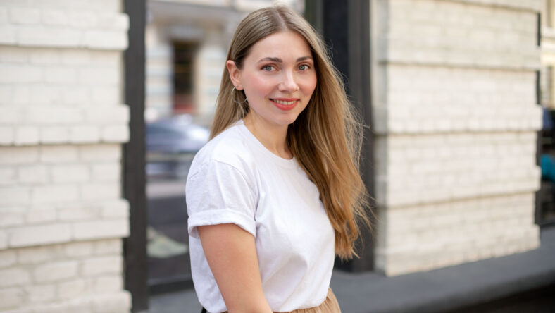 beautiful caucasian girl with blonde hair in a white t-shirt looks at the camera and smiles