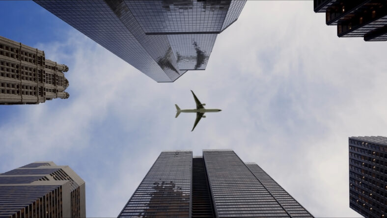 Bottom view of a passenger long-haul aircraft liner flying over skyscrapers in the business center of a large city. Reflections of the plane in the windows of buildings on a sunny day. Travel concept.