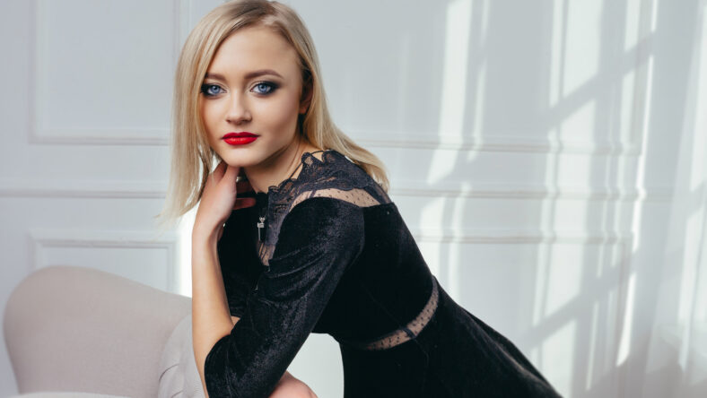 Studio shot of young and beautiful girl in black dress wearing in studio.