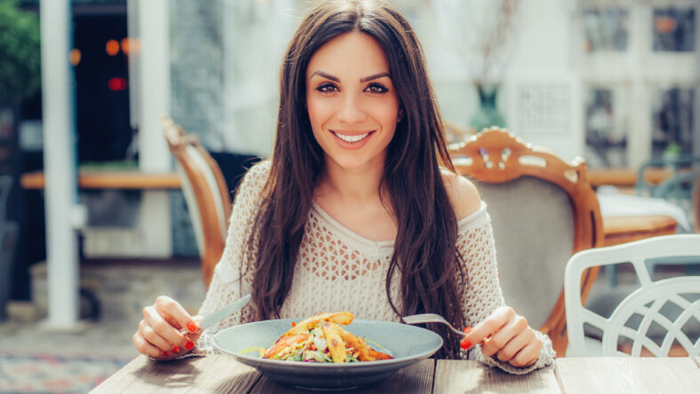 Young woman enjoying food in a restaurant, having her lunch break. Close up