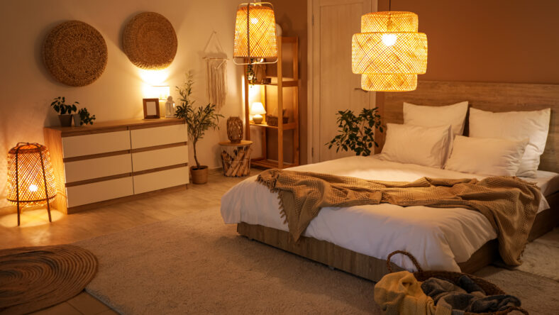 Interior of bedroom with commode, door and glowing lamps at night