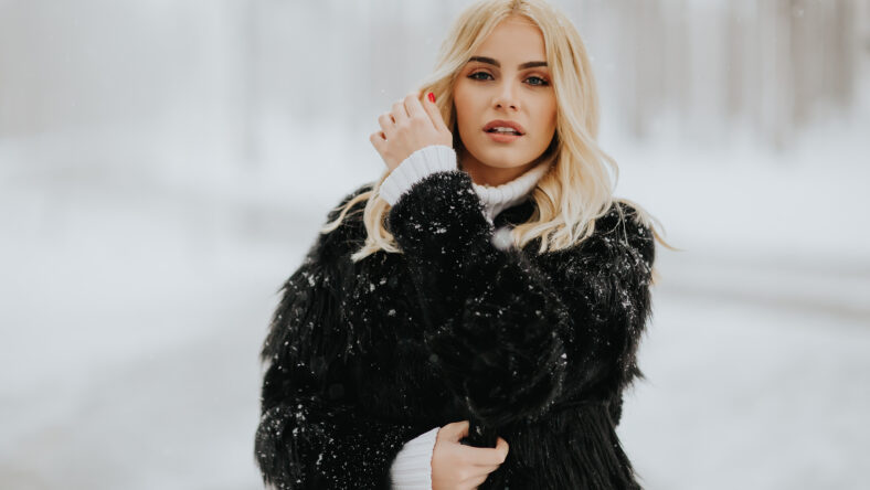 Portrait of blonde woman outside in snow winter coat