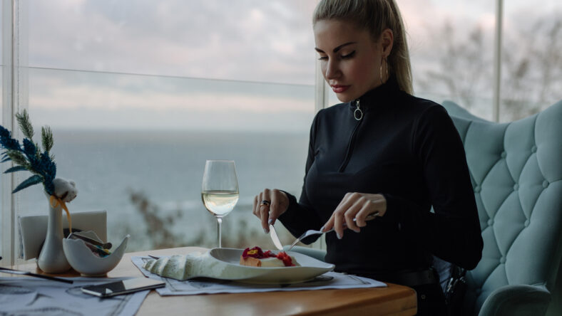 Luxury woman eating cake in restaurant with sea view