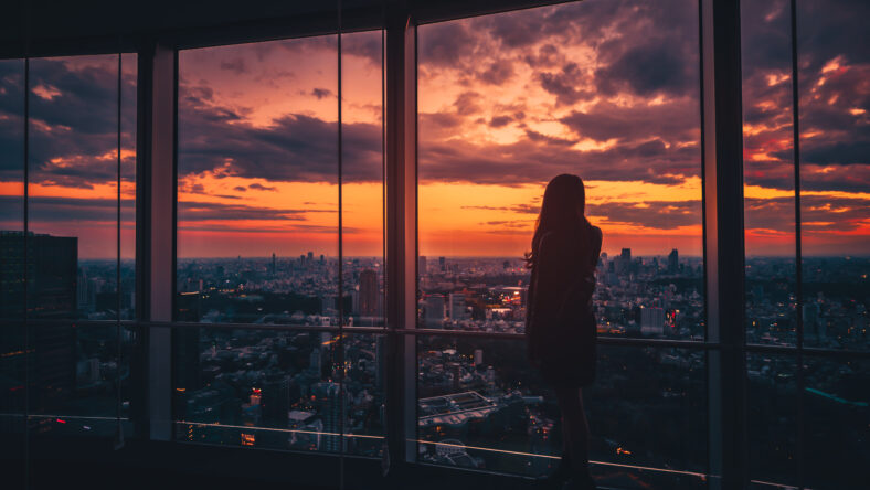 Rear view of Traveler woman looking Tokyo Skyline and view of skyscrapers on the observation deck at sunset in Japan. Vintage tone