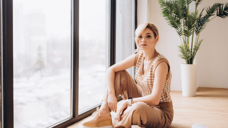 Stylish blonde woman in neutral clothes reads a fashion magazine. Soft selective focus, artistic noise.