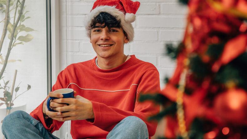 teenager at home with christmas tree and cup
