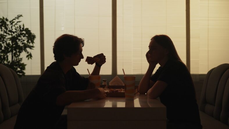Everyday life and people relationships concept. Portrait of couple in cafeteria. Silhouette of man and girl on a date sitting at the bistro bar together, male eats pizza slice female looking thinking.