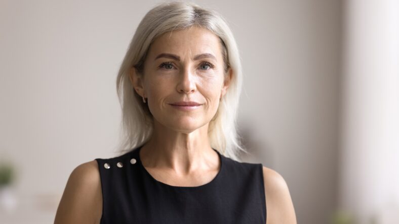 Middle-aged businesswoman look at camera with serious face expression, standing, pose at home office, head shot close up portrait. Midlife, natural beauty, profession occupation person profile picture