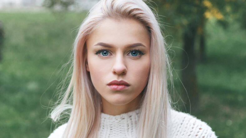 Portrait of a beautiful serious blonde girl in a white knitted sweater