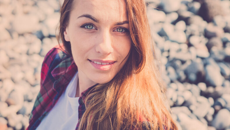 Attractive caucasian young woman smile and look at the camera - sunlight and blue eyes - vintage filter - defocused pattern background