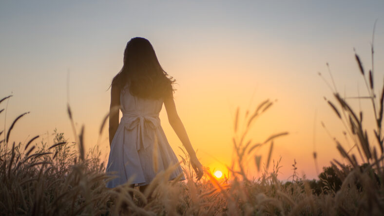 Trendy girl in stylish summer dress feeling free in the field with flowers in sunshine,enjoying nature, Beautiful Teenage Model in the Spring Field, Sun Light.