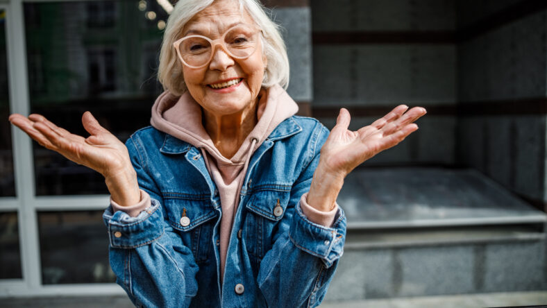 Smiling old lady in jeans jacket is enjoying time in open air