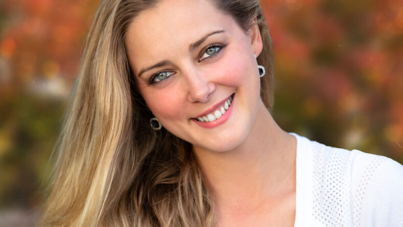 Headshot of a beautiful blonde woman outdoors, closeup smiling portrait, happy and cheerful