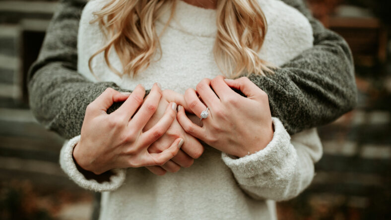 Couple holding hands with engagement ring