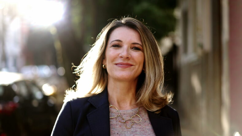 Smiling confident older woman walking outdoors with sun backlight. Proud mature lady walks forward face closeup