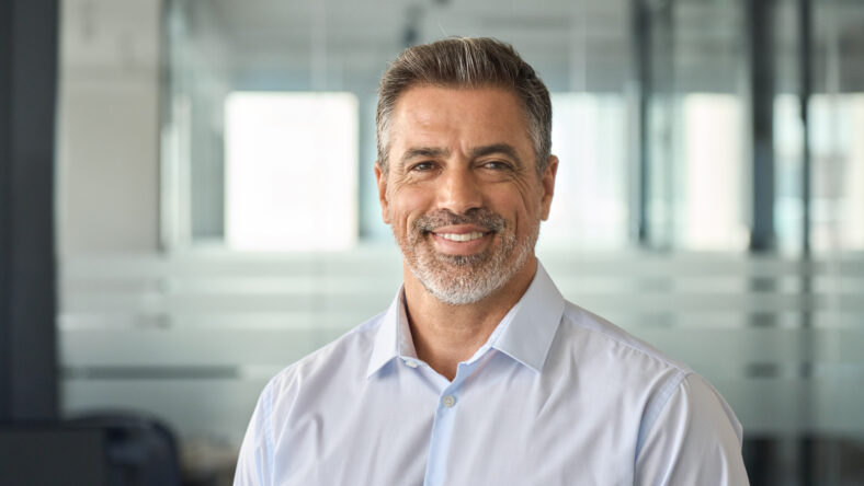 Happy mid aged older business man executive standing in office. Smiling 50 year old mature confident professional manager, confident businessman investor looking at camera, headshot close up portrait.