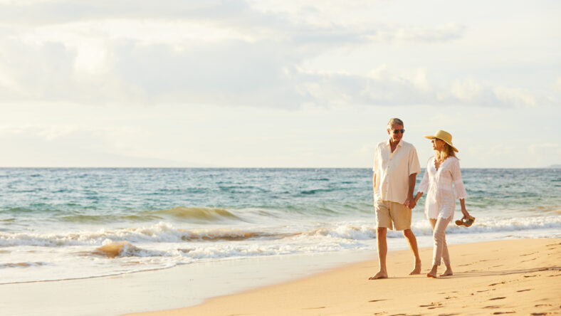 Happy Romantic Middle Aged Couple Enjoying Beautiful Sunset Walk on the Beach. Travel Vacation Retirement Lifestyle Concept