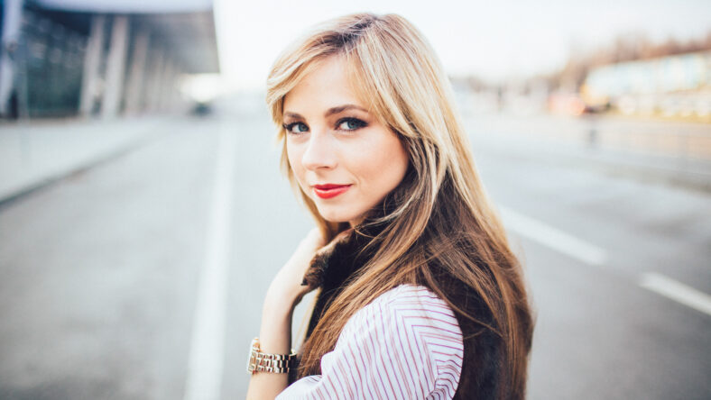 pretty young blonde woman standing in a street