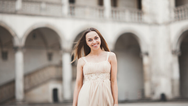 Beautiful girl with long hair posing in old castle with columns. Krakow Vavel.