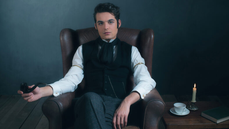 Retro victorian man sitting in leather chair holding pipe.