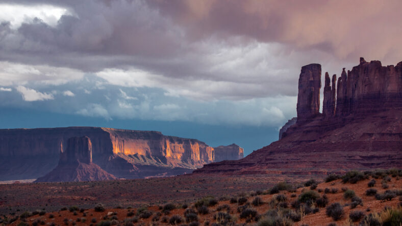 Light from a setting sun shines on Monument Valley along the Utah/Arizona border.