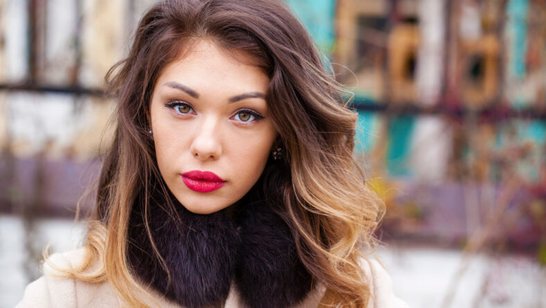 Young brunette woman in gray woolen coat on background autumn park