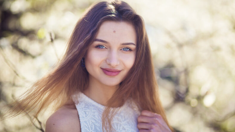 Young beauty girl posing in garden with magnolia blossom